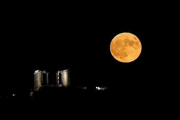 A full moon rises behind the Temple of Poseidon in Cape Sounion, near Athens