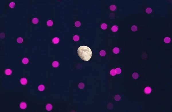 The moon is seen behind decorative lights prepared for the upcoming Mid-Autumn or Moon