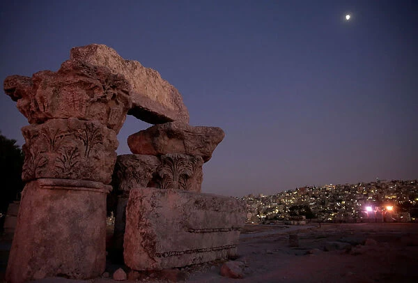 The moon is seen over houses and the Temple of Hercules at Amman Citadel, an ancient