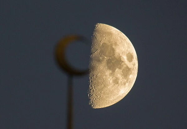 The moon is seen behind a mosque in the city of Almaty