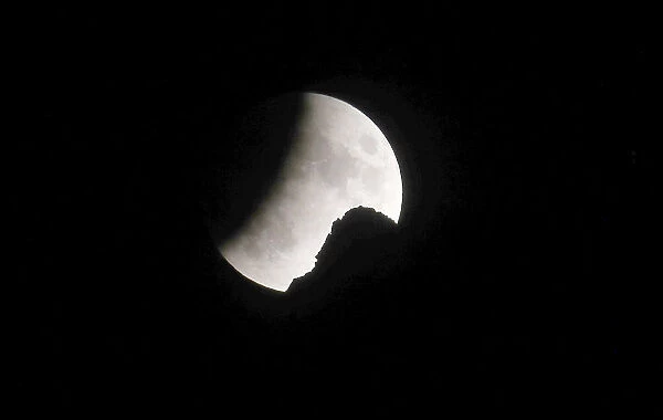 The moon is seen during a partial lunar eclipse behind a peak in the north-eastern Swiss