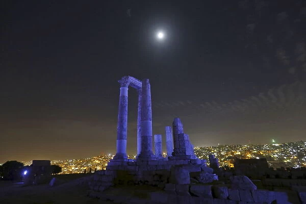 The moon is seen over the Roman pillars of the Temple of Hercules as it is lit up