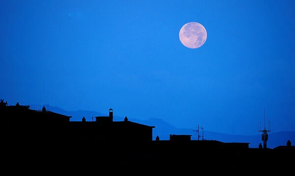 The full moon is seen over rooftops at the San Fermin festival in Pamplona