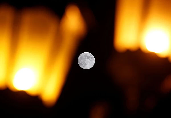 The full moon is seen behind street lights in Valletta