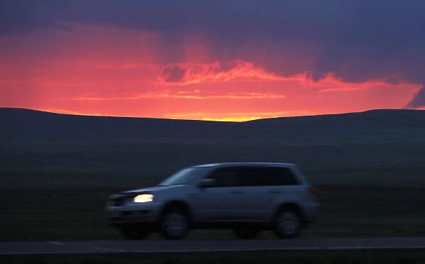 A motorist drives along a highway during sunset south of Russias Siberian city of