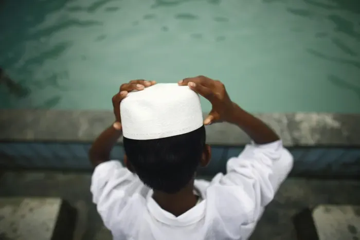 Framed Print : A Muslim boy puts on his hat after washing his face prior to Eid al-Fitr prayers Framed Print : A Muslim boy puts on his hat after washing his face prior to Eid al-Fitr prayers