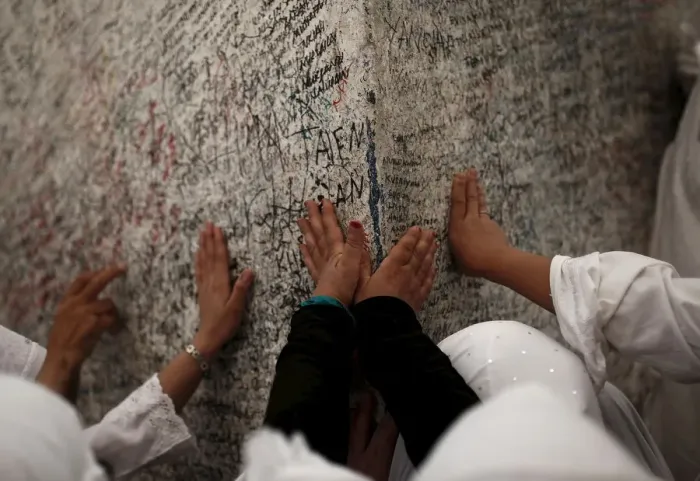 Framed Print : Muslim pilgrims touch a rock atop Mount Mercy on the plains of Arafat during the annual