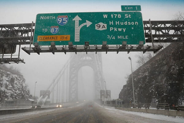 A nearly empty snow-covered roadway entrance to the George Washington Bridge between New