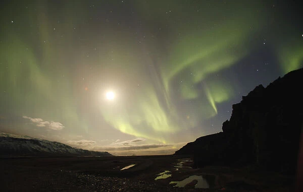 The Northern Lights are seen through a valley leading away from Iceland s
