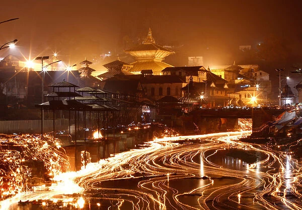 Oil lamps offered by devotees illuminate the Bagmati River flowing through the premises