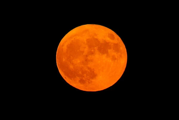 An orange full moon rises in the Strait of Gibraltar
