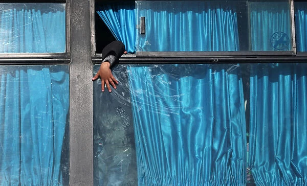 A Palestinian boy puts his hand out of a bus window as he waits with his family to cross