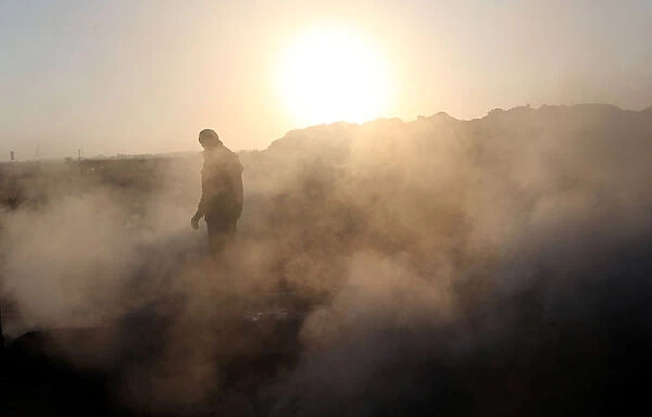 A Palestinian demonstrator is seen as smoke rises from a fire caused by objects dropped