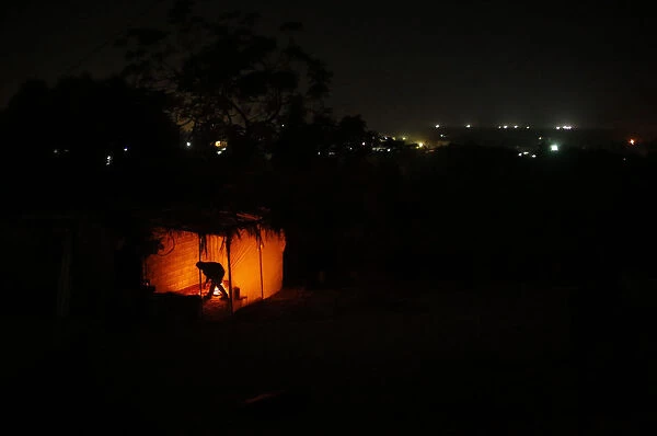 A Palestinian man ignites a fire at his makeshift shelter during a power cut in the