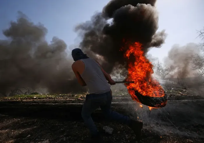 Framed Print : Palestinian protester moves a burning tyre during clashes with Israeli troops following a Framed Print : Palestinian protester moves a burning tyre during clashes with Israeli troops following a