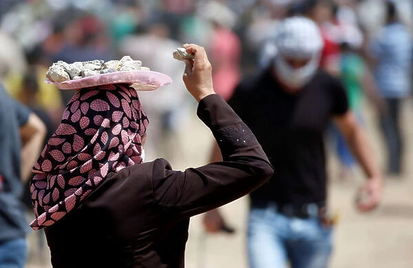Palestinian woman carries a tray with stones on her head during a protest marking al-Quds
