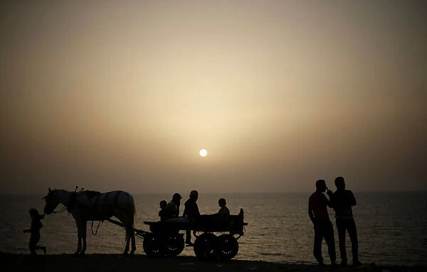 Palestinians ride a horse-drawn cart on a beach at Deir al-Balah refugee camp in the