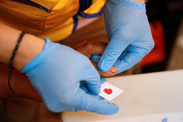 A paramedic takes a blood sample for DNA testing from a resident looking for a relative