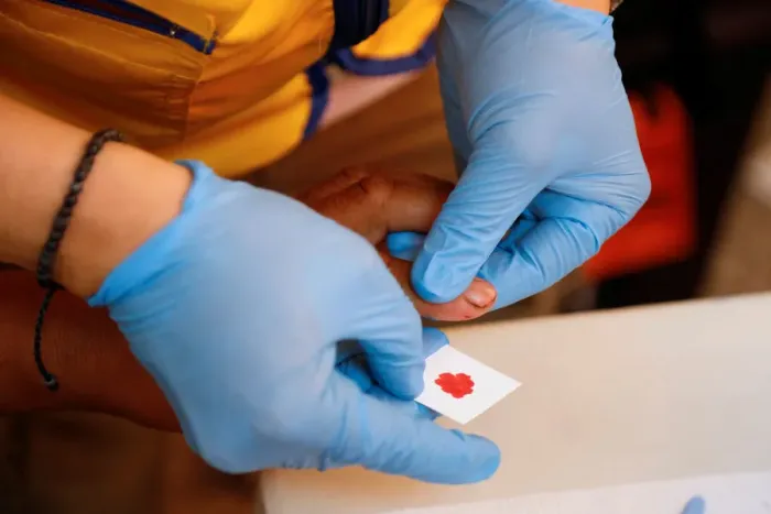 Framed Print : A paramedic takes a blood sample for DNA testing from a resident looking for a relative Framed Print : A paramedic takes a blood sample for DNA testing from a resident looking for a relative