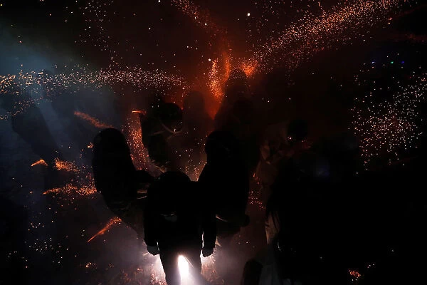 Participants wearing motorcycle helmets get sprayed with firecrackers