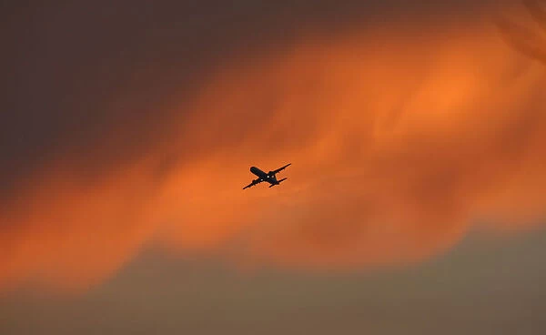 A passenger aircraft flies against the backdrop of monsoon clouds in New Delhi