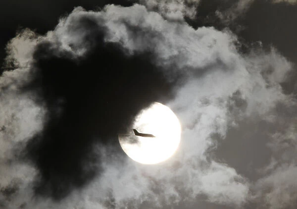 A passenger aircraft is silhouetted against the rising sun after taking off from New