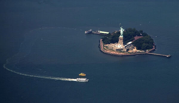 A passenger ferry leaves the The Statue of Liberty and Liberty Island seen from this