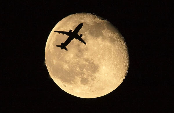 A passenger jet flies past the moon over Shanghai