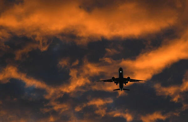 A passenger plane flies towards Heathrow airport at dawn in London, Britain