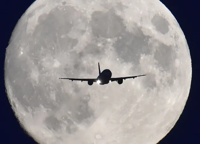 Framed Print : A passenger plane passes in front of the full moon as it makes a final landing approach
