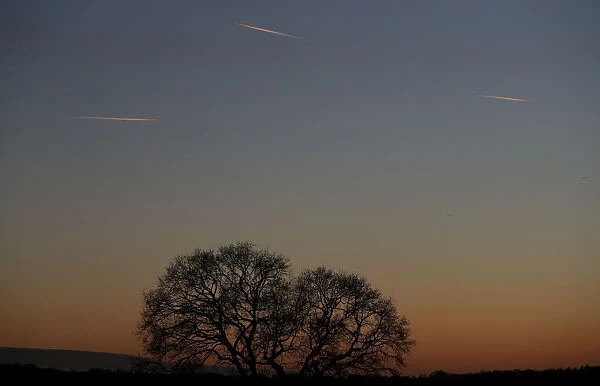 Passenger planes leave behind contrails as they fly in the skies over London Luton Airport