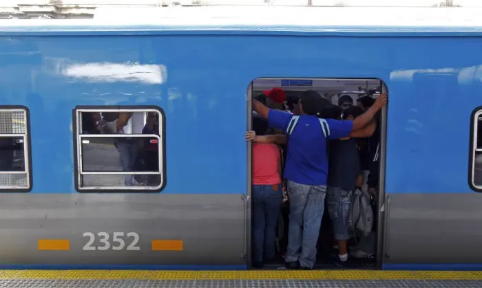 Framed Print : Passengers stand on the edge of a commuter train door at the Once train station in