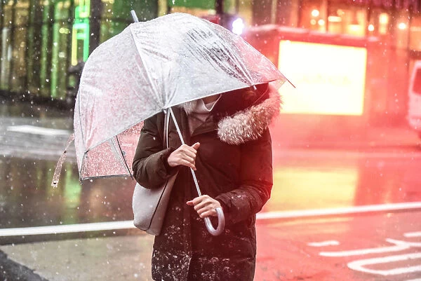 A pedestrian carries an umbrella through the snow during a nor easter storm in New York