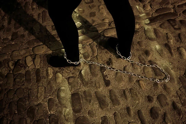 A penitent drags a chain as she takes part as penitent of Nuestro Padre Jesus Nazareno
