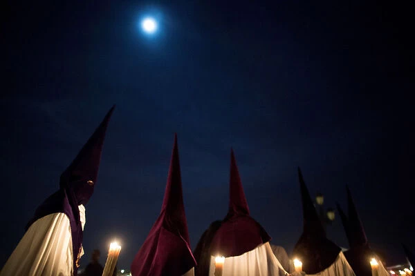Penitents of La Estrella brotherhood take part in a procession during Holy Week in the