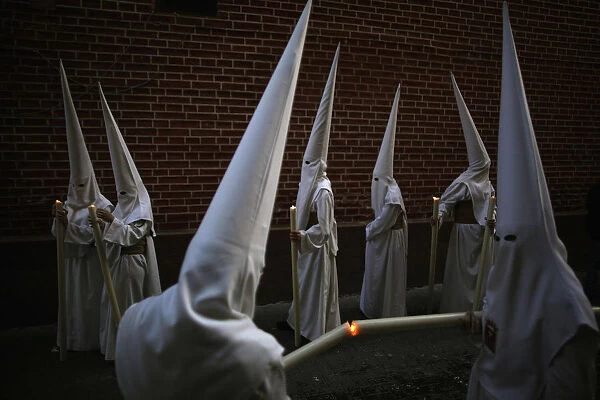 Penitents light their candles as they take part in the Humildad brotherhood Palm Sunday