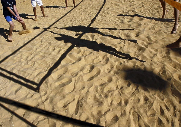 People cast shadows on the sand as they compete in a volleyball game in Jerusalem