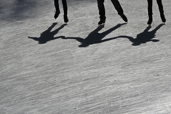 People cast their shadows as they skate on the Wollman Rink in Central Park in the