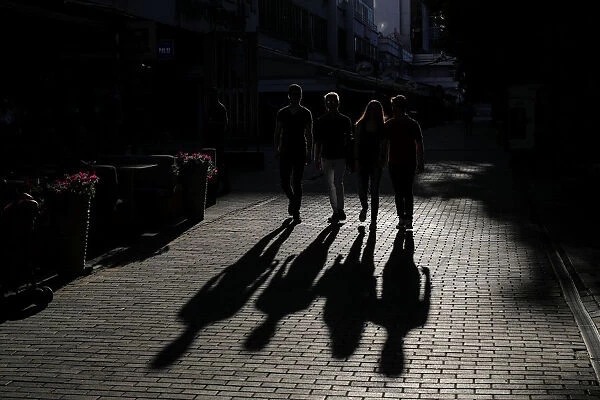 People cast shadows as they walk on a street in central Skopje, Macedonia