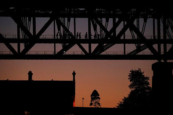 People climb the Sydney Harbour Bridge at sunset, in Sydney