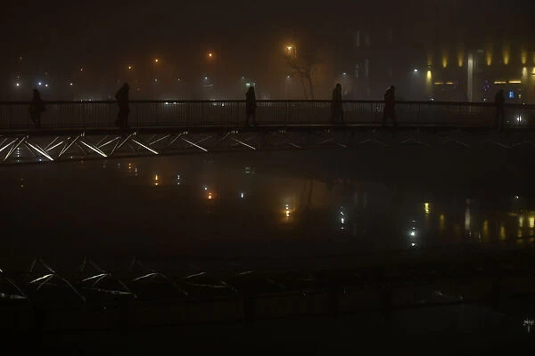 People cross a bridge over the river Liffey during heavy fog in Dublin