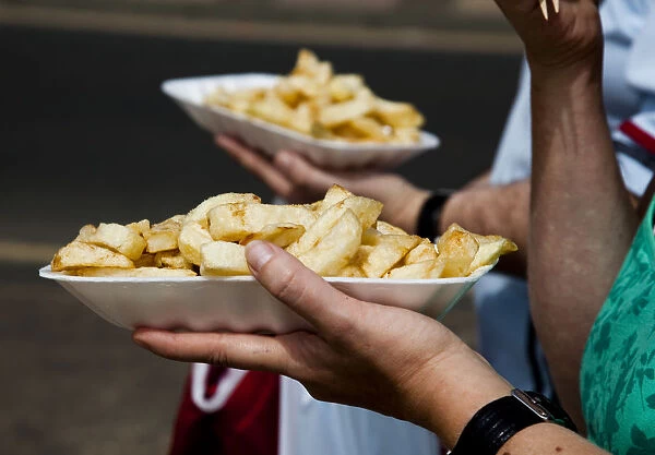 People eat chips whilst walking along the promenade at the British holiday resort