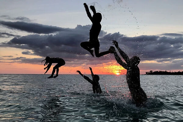People have fun on a beach during sunset at Ko Kut island in Trat Province