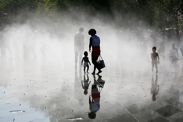 People gather near fountains of water as they cool off at the Miroir d Eau