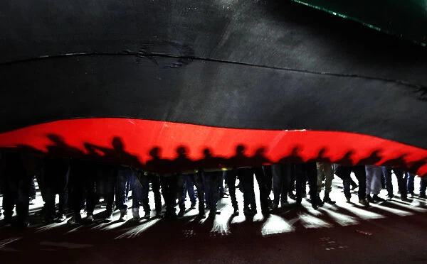 People hold a giant Libyan flag during a march to Martyrs Square in Tripoli