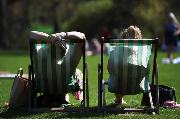 People lounge on deckchairs in the sunshine in St James Park, London