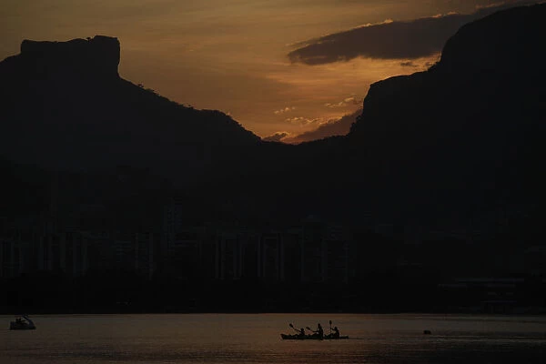 People paddle their canoe at Rodrigo de Freitas Lagoon as the sun sets in Rio de Janeiro