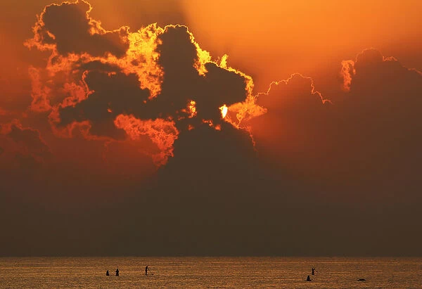 People paddle on a stand-up board during sunrise in a beach in Larnaca