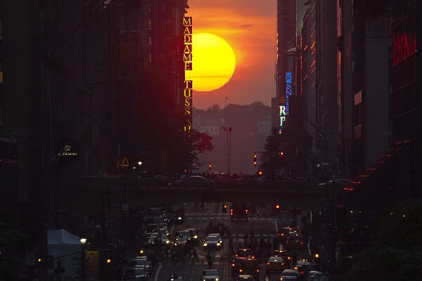 People take pictures of sunset on 42nd street, during the Manhattanhenge in New York