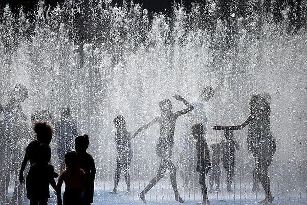 People play amongst the fountains outside the Royal Festival Hall in London